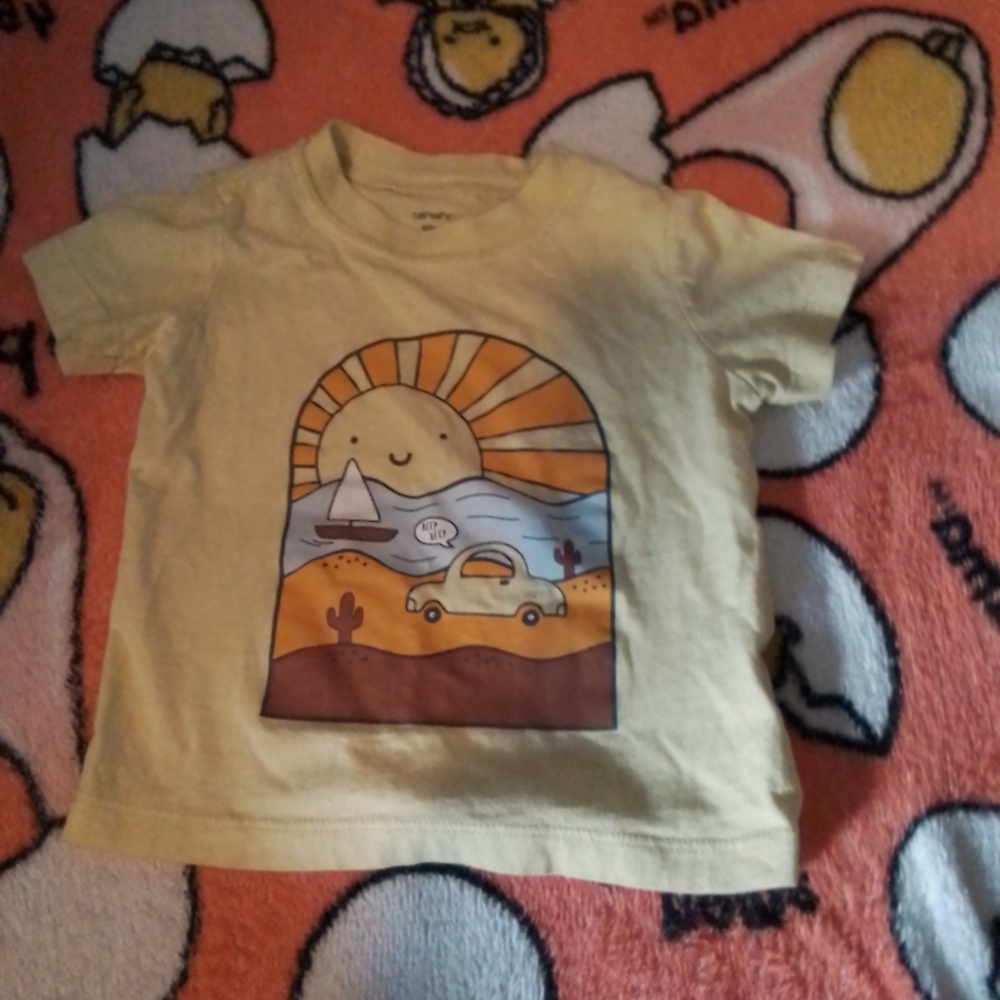 A short sleeve shirt with a sun,water,boat and car on it.